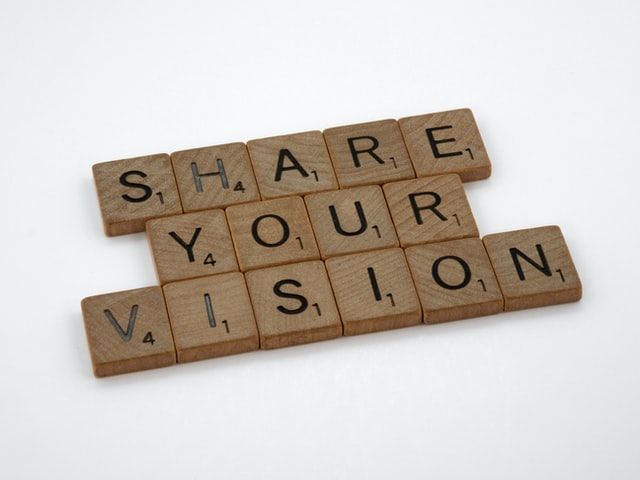 A photo of Scrabble tiles that spell out "SHARE YOUR VISION"