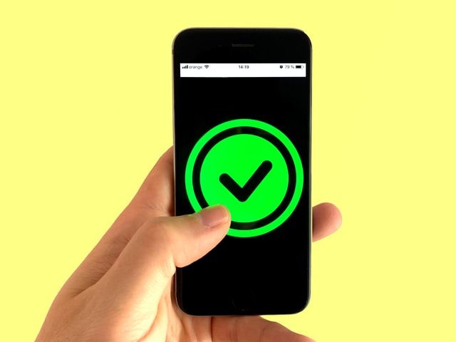 An image of a mobile phone with a green circle and a tick in the centre against a yellow background. 