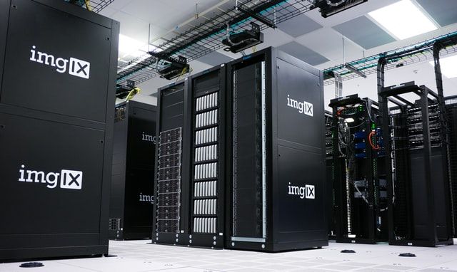 Photo of a server room full of black computers and server racks. 